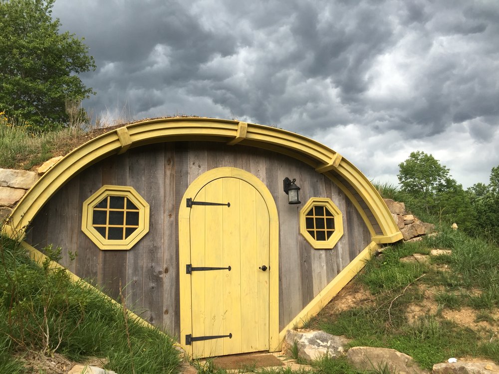 underground hut with a small yellow door entrance, looks like a hobbit home.