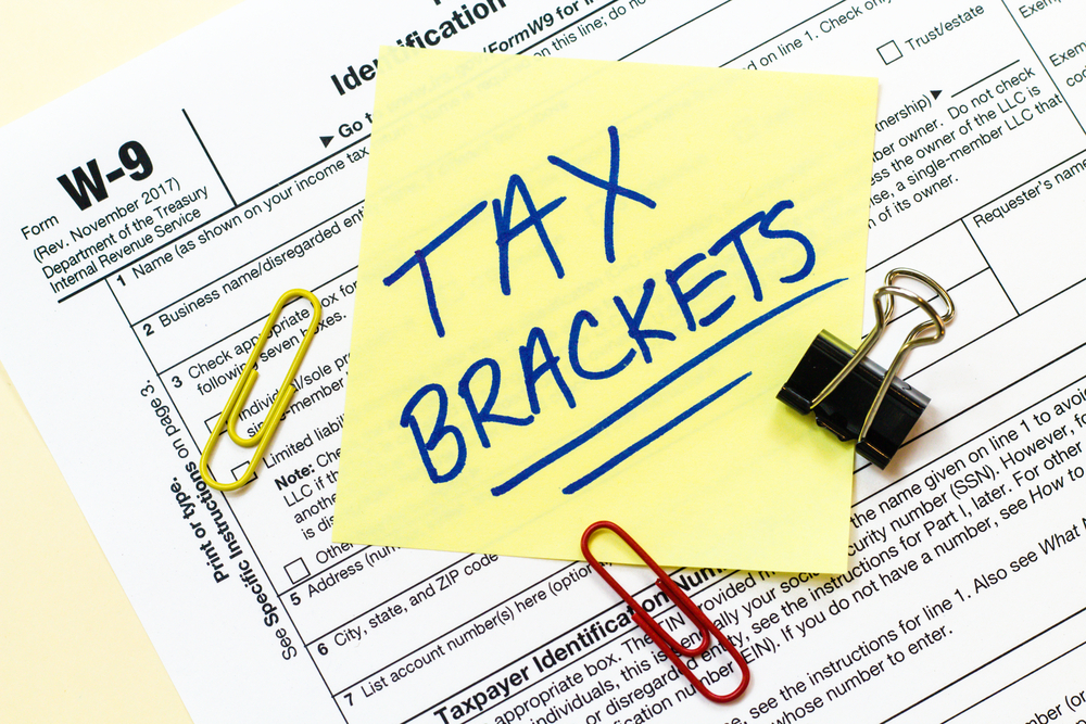 Tax forms and Tax Brackets written on sticky notes