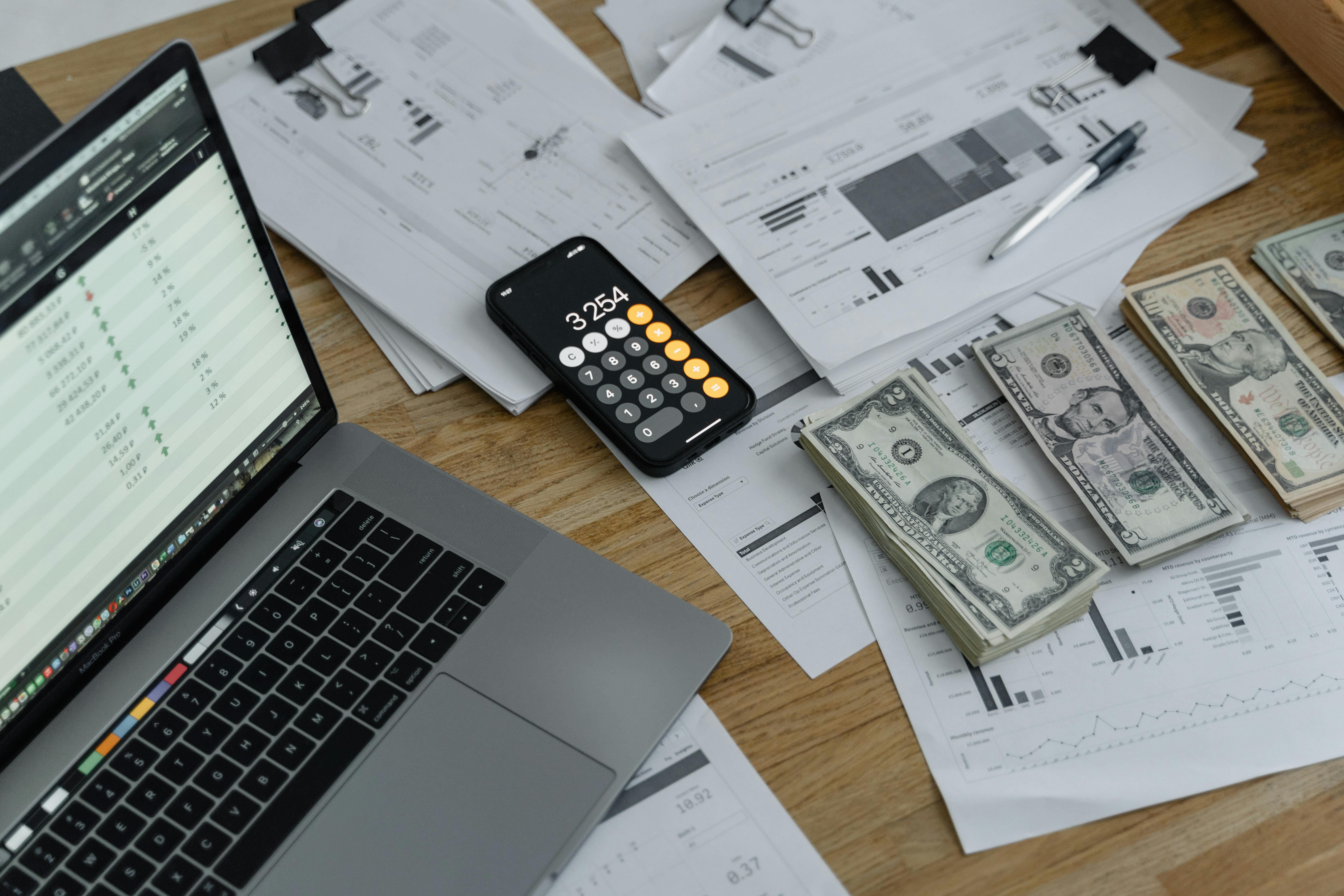 Laptop, calculator, papers and cash on the table