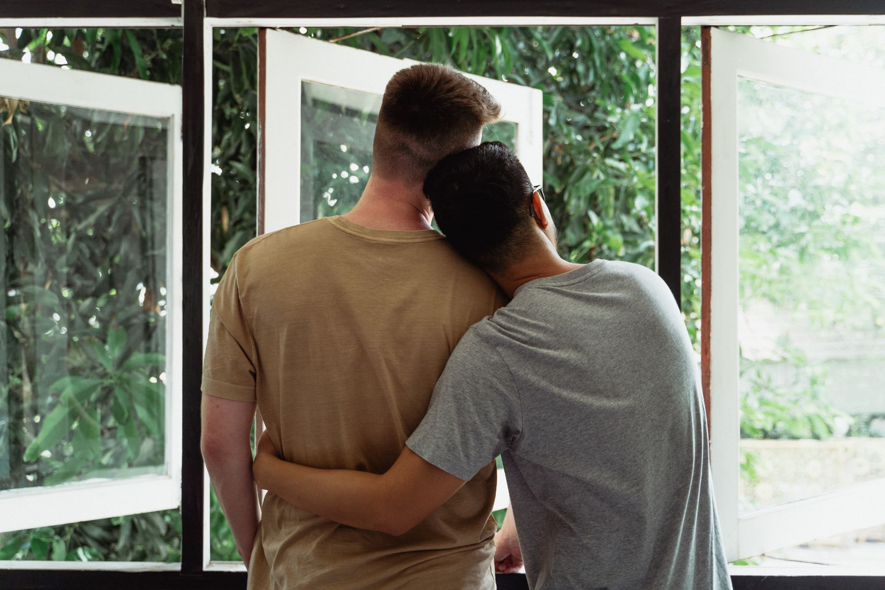 Two men hugging eachother and looking out the window in their new home