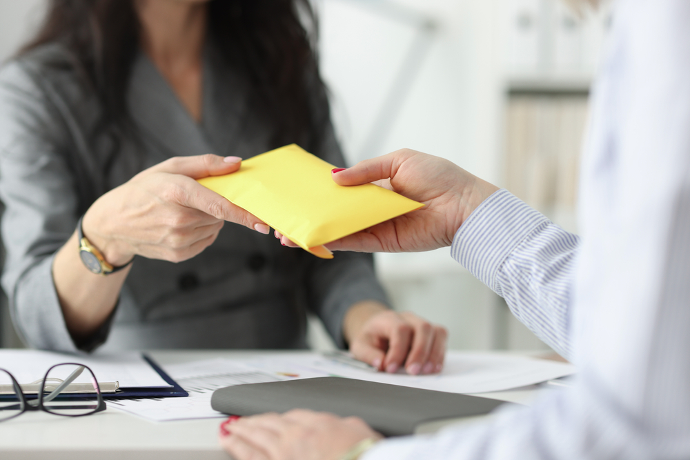 Woman Handing Out An Envelope
