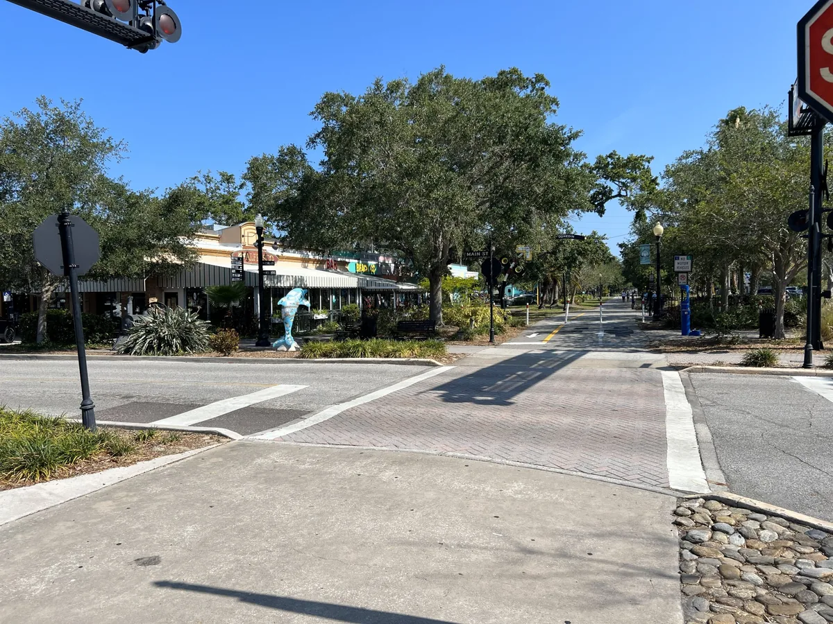 Pinellas Trail running through downtown Dunedin, Florida, with shops, trees, and a walkable streetscape