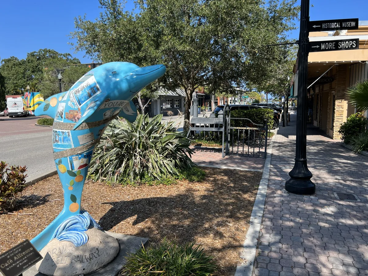 Iconic dolphin statue along the sidewalk in downtown Dunedin, Florida, near shops and the Pinellas Trail
