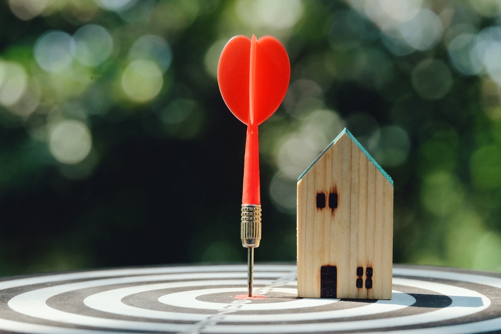 A photo of a dart hitting a bullseye with a small house next to it