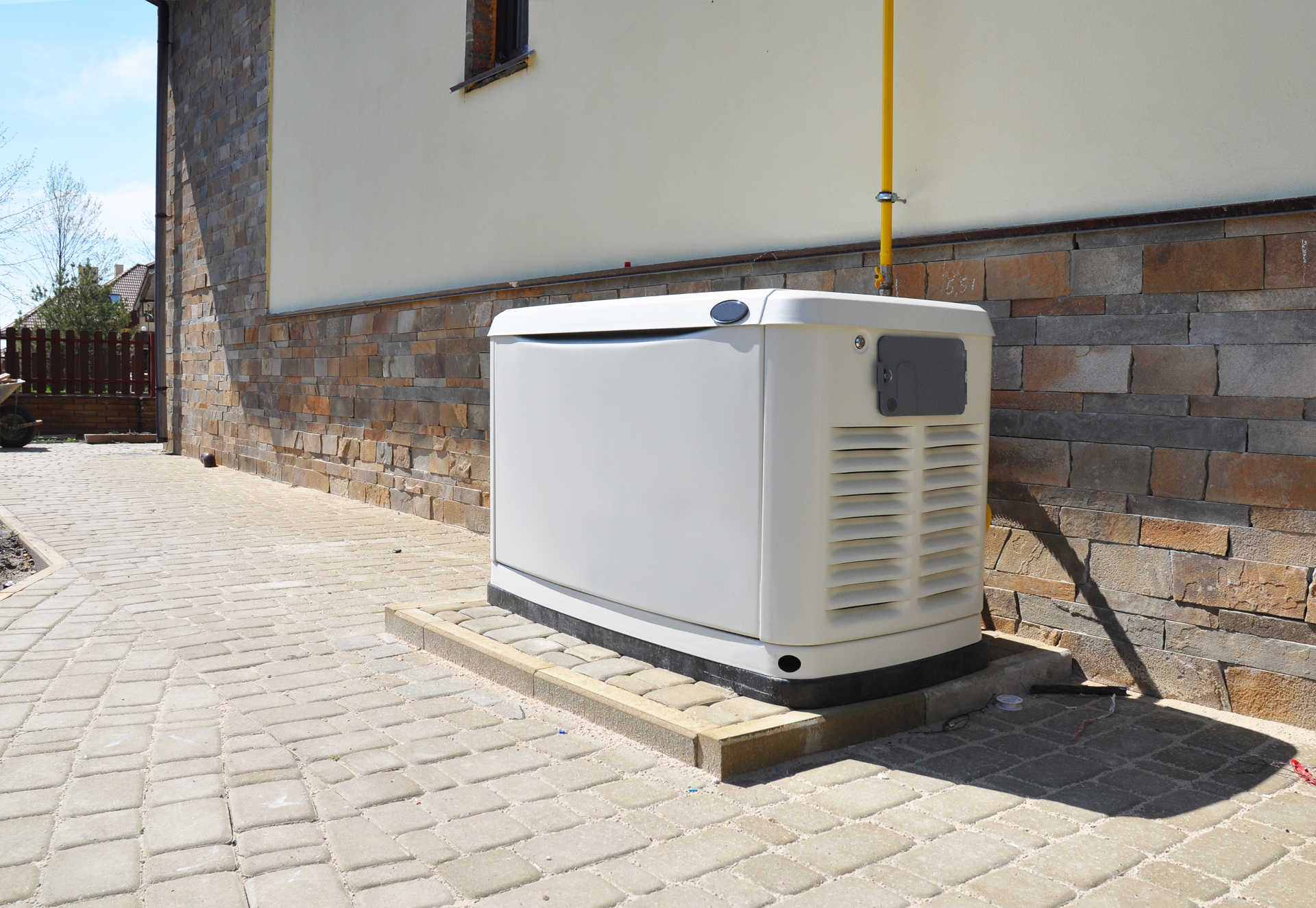 A white home generator on a brick patio.