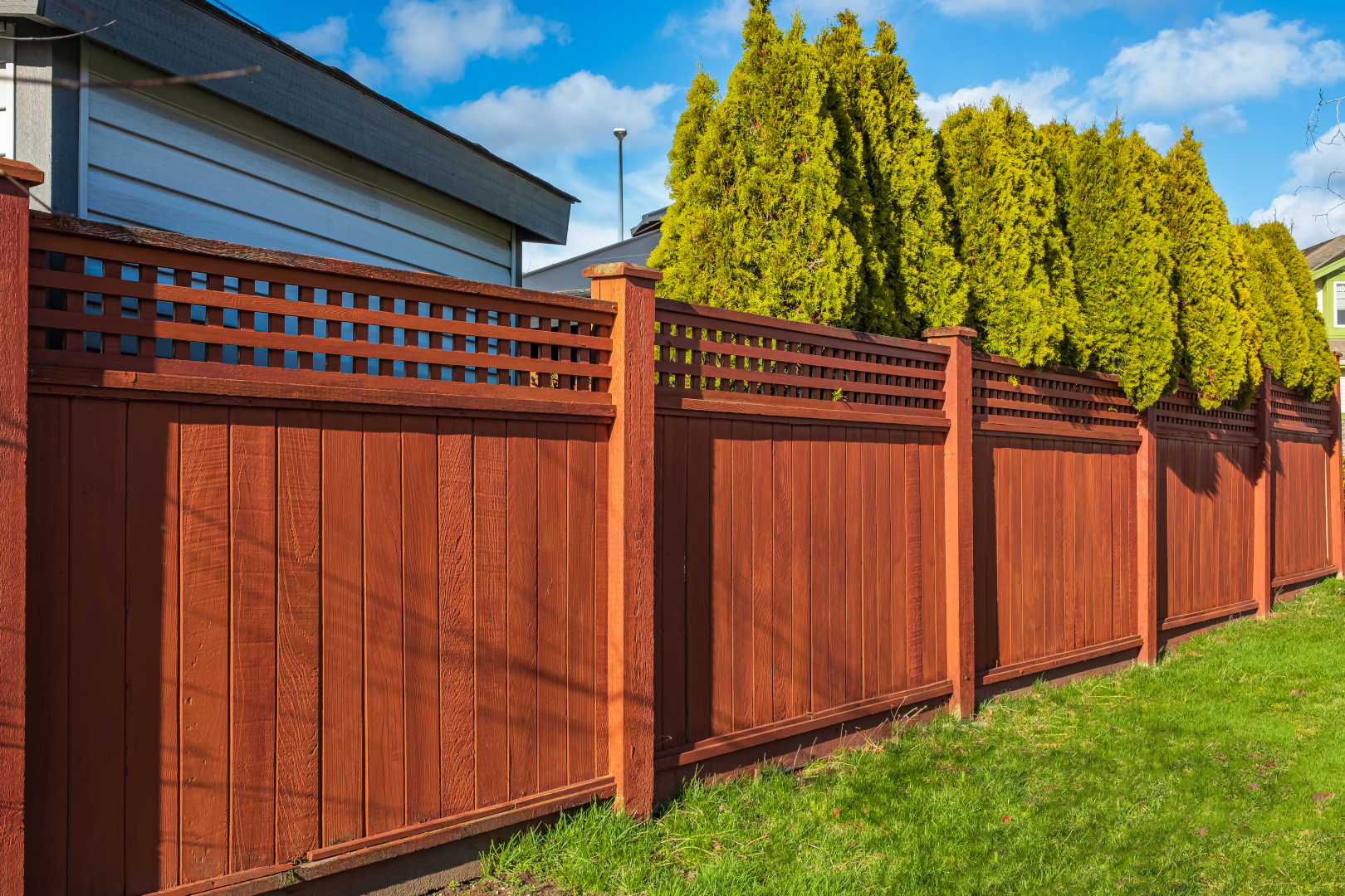 A wooden fence surrounding a lush green lawn.