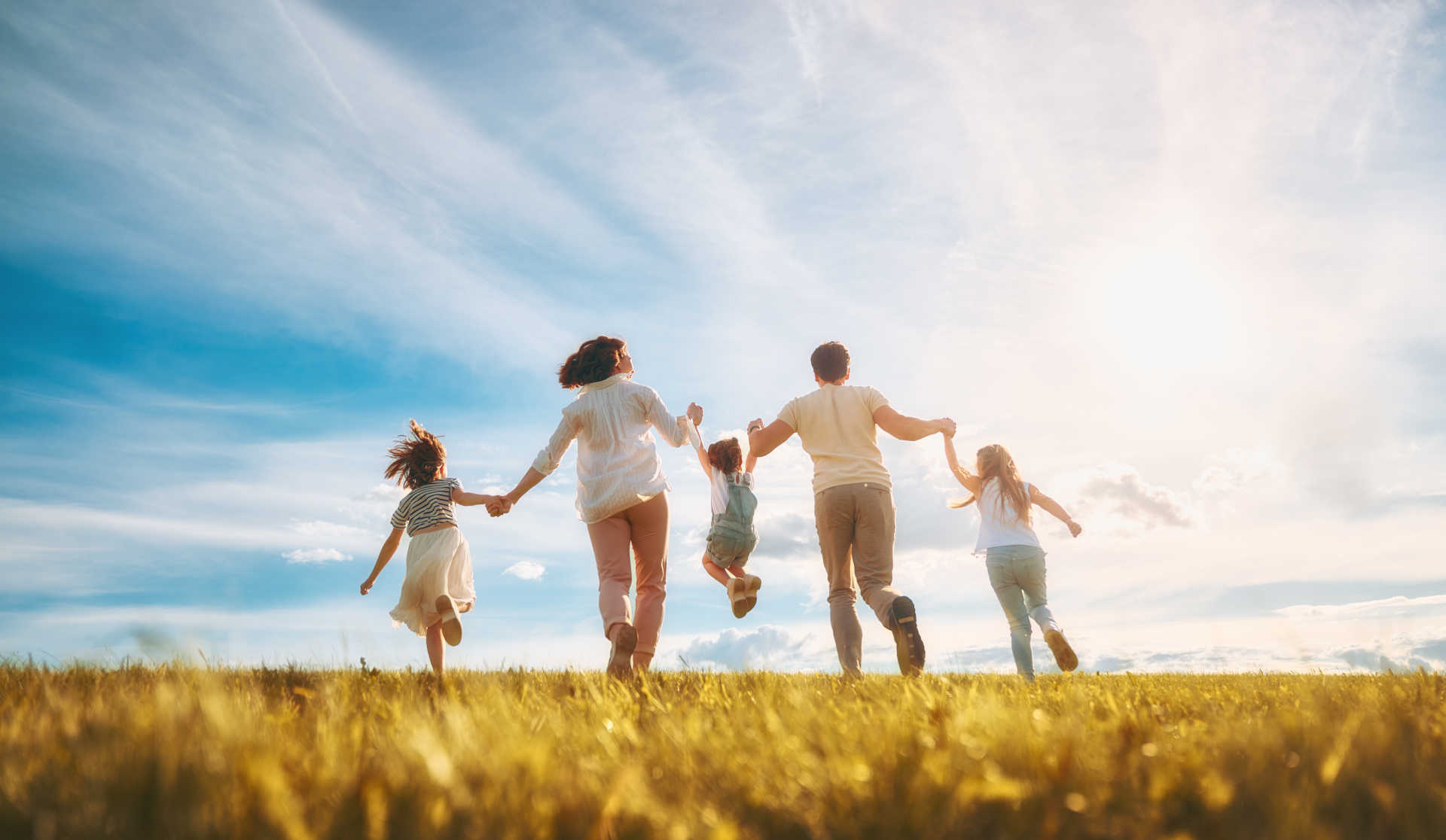A joyful family running together in a sunlit field, laughter and happiness filling the air around them.