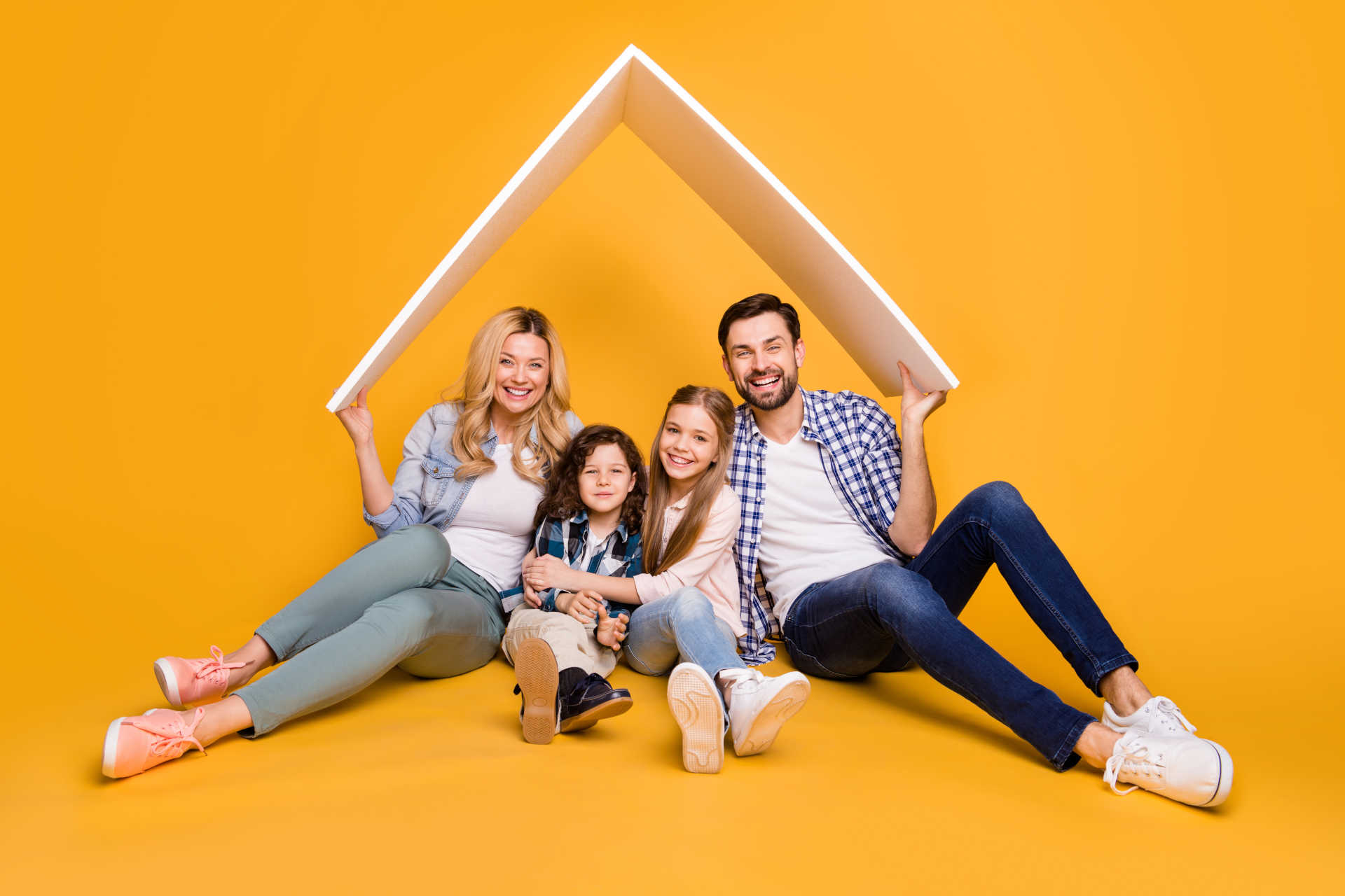 A happy family poses together against a bright yellow background, with a cozy house illustrated nearby.