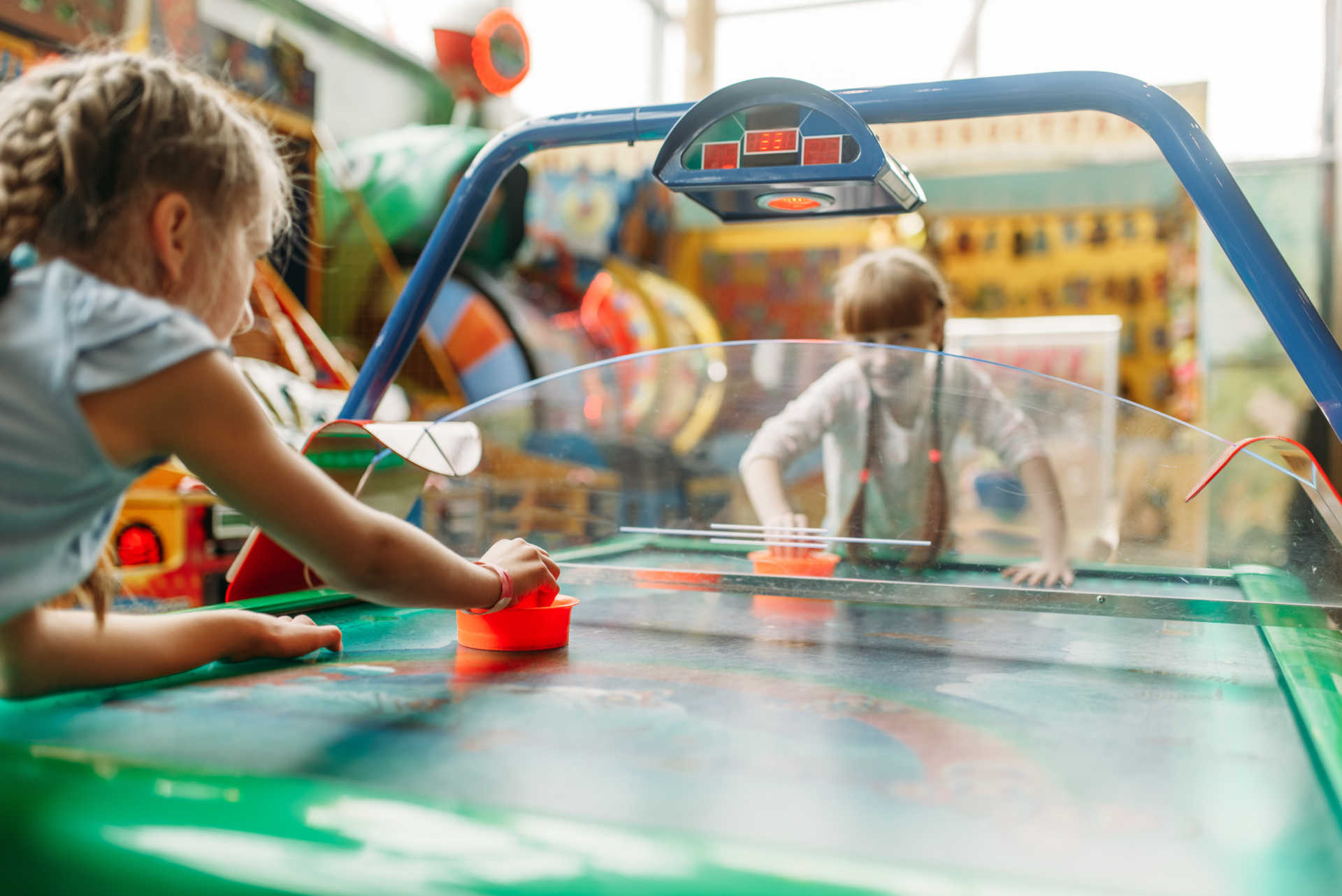 Two children joyfully playing together at a game table in a bright, cheerful room filled with toys and laughter.