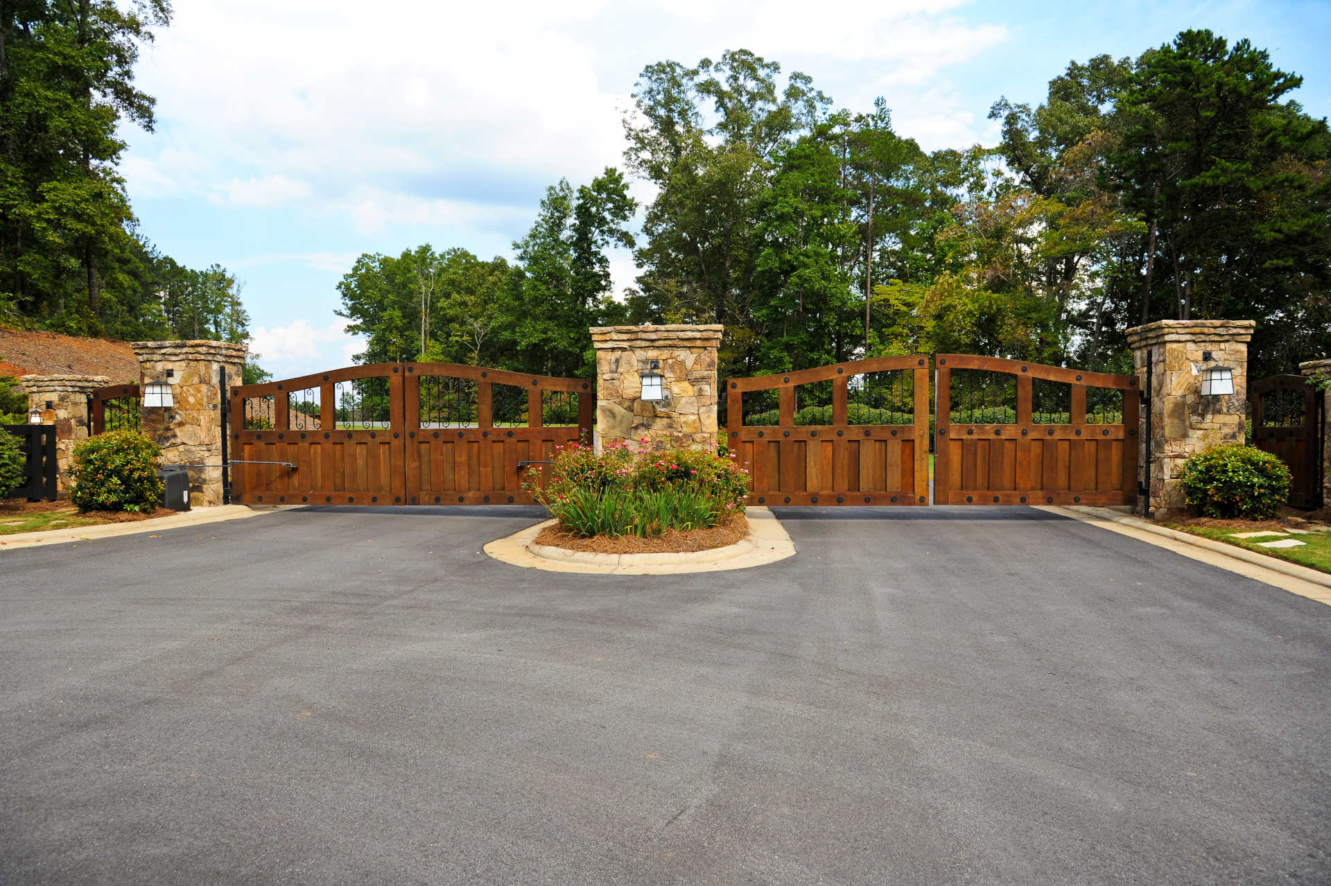 A serene driveway featuring two large, rustic wooden gates, inviting you into a beautiful property beyond.