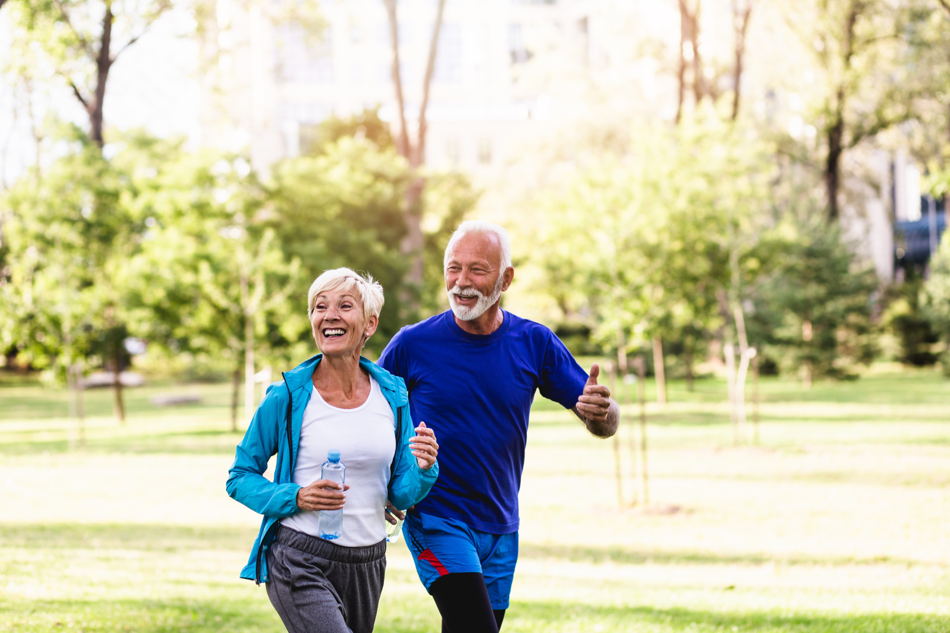 A joyful senior couple jogging together in a sunny park, enjoying their exercise and each other's company.