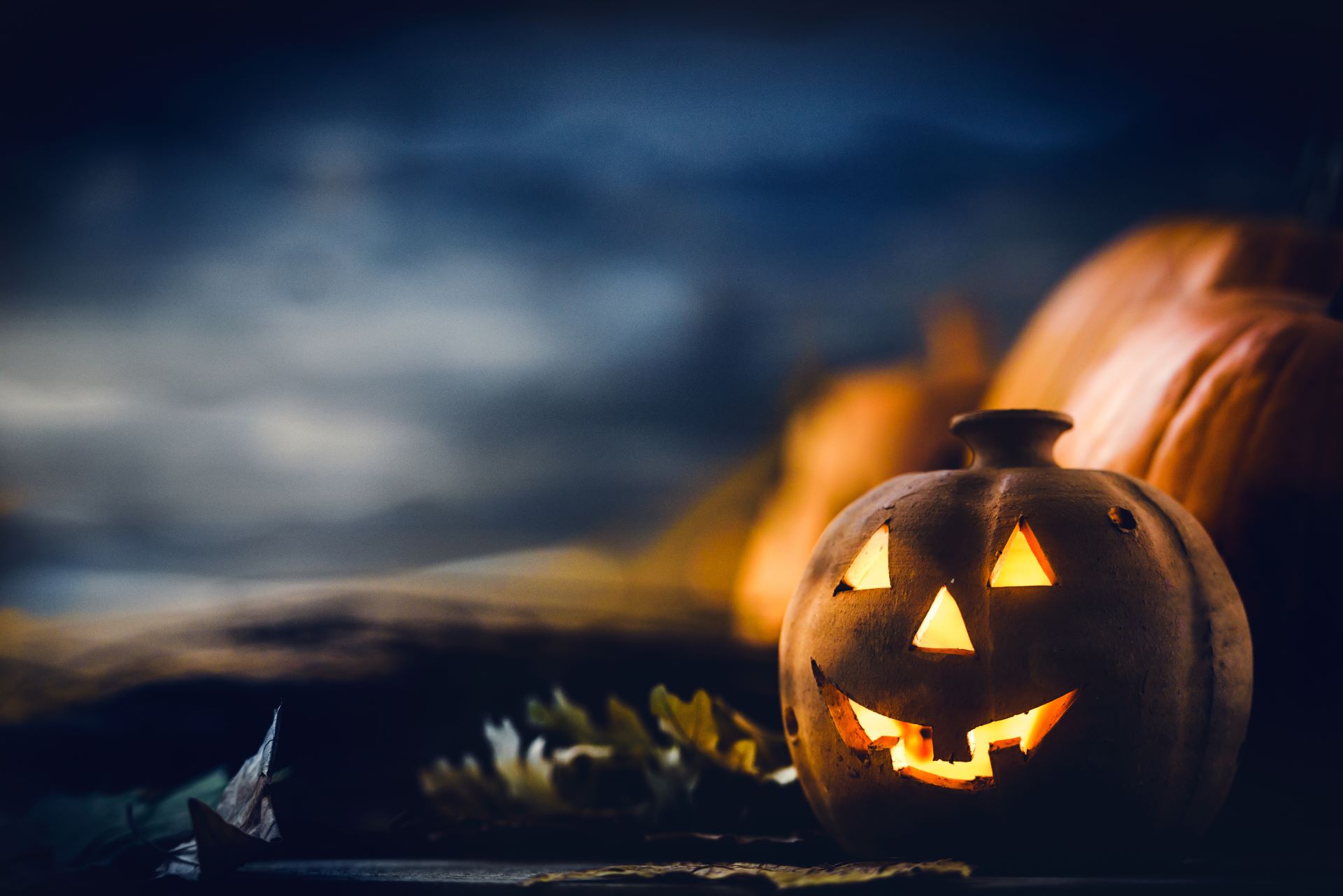 A collection of Halloween pumpkins with glowing eyes set against a dark background, creating an eerie atmosphere.