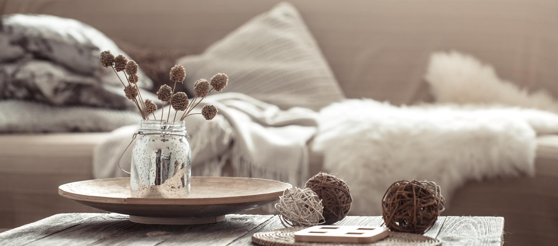 A wooden table adorned with a vase containing an arrangement of dried flowers, showcasing a rustic and natural aesthetic.