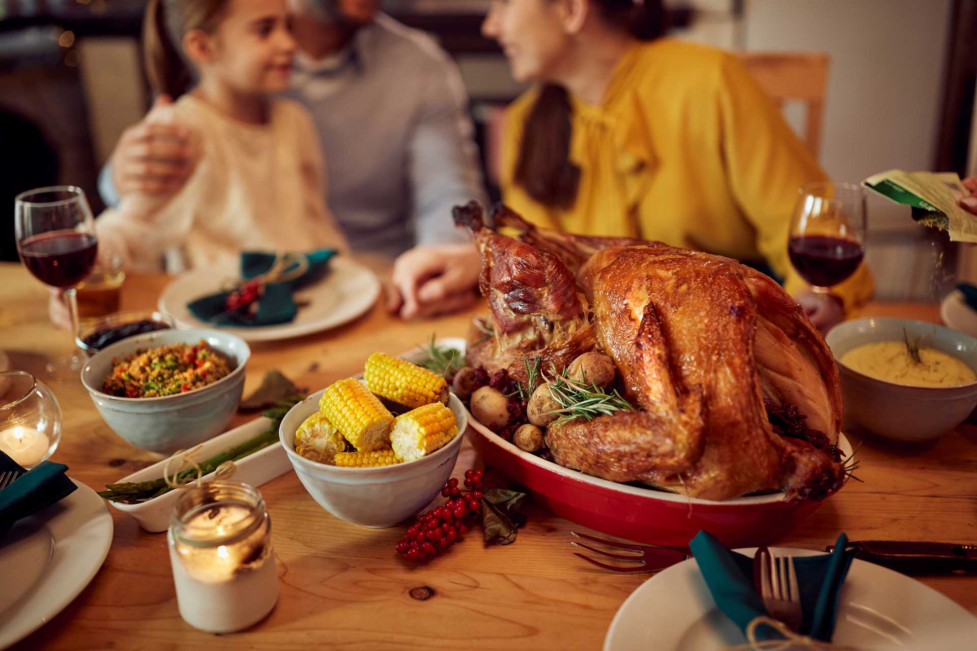 A family gathers around a table, sharing a joyful Thanksgiving dinner with a feast of traditional dishes.