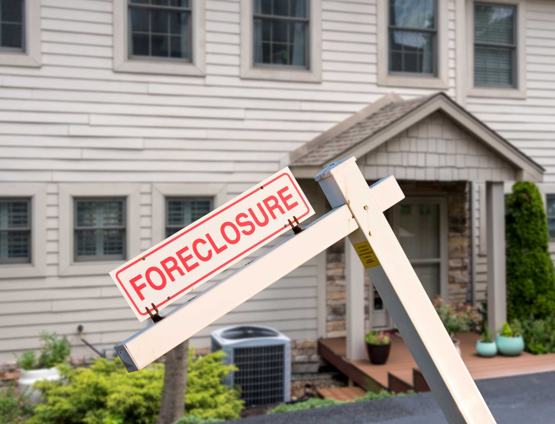 Foreclosure signs displayed prominently in front of a residential property, indicating financial distress.