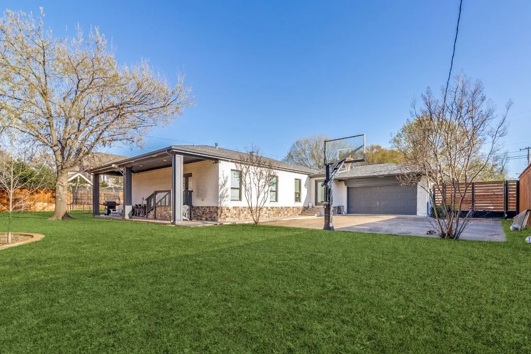 A residential home with a basketball hoop and a well-maintained grassy yard.