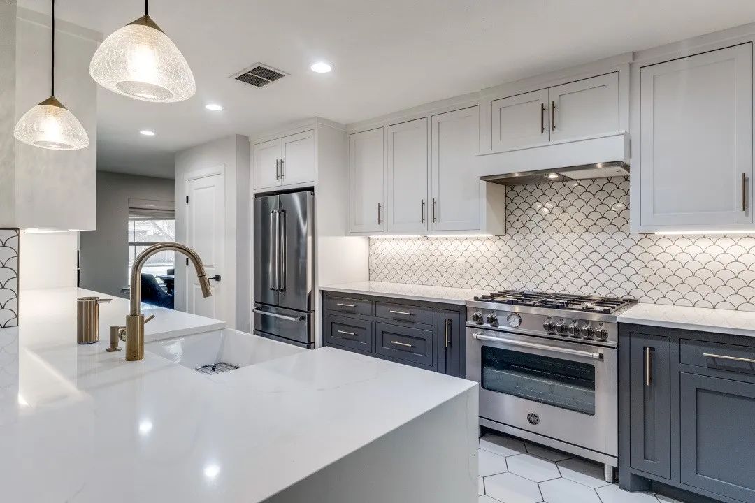 A modern kitchen featuring white cabinets and sleek gray countertops.