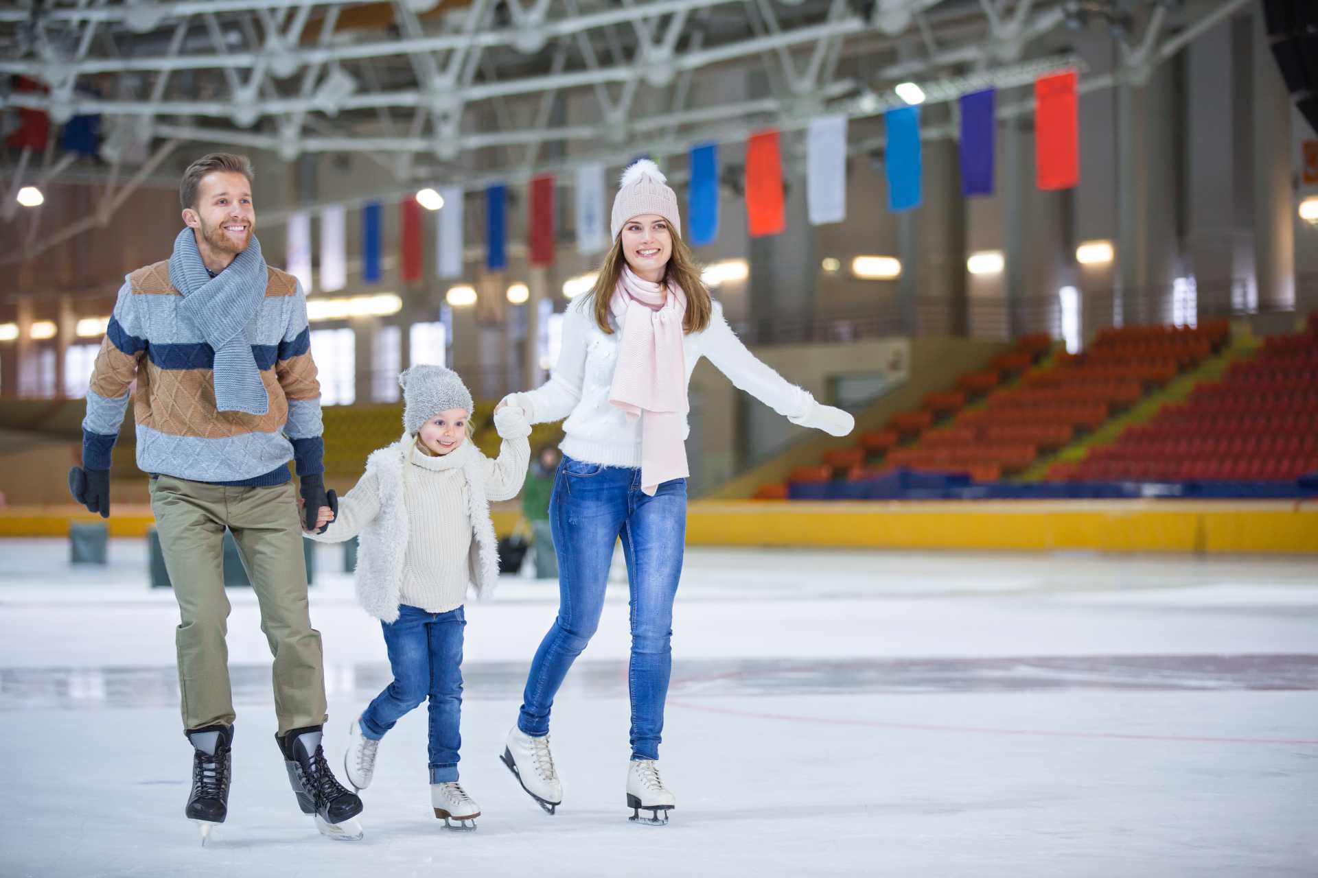 Fun family activities at the ice skating rink – parents and child enjoying quality time together on the ice.
