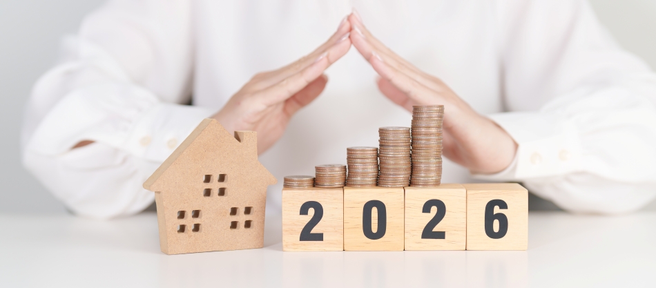 Hands protecting a small wooden house and stacked coins on blocks reading 2026, symbolizing budgeting, savings, and Top Home Improvements planning for future home upgrades and financial security.