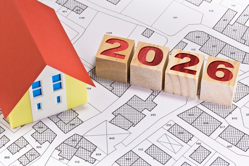 2026 Housing Market Outlook showing a model home and wooden blocks displaying 2026 over a residential lot map, representing North Texas real estate market trends, home prices, and buyer seller forecasts.