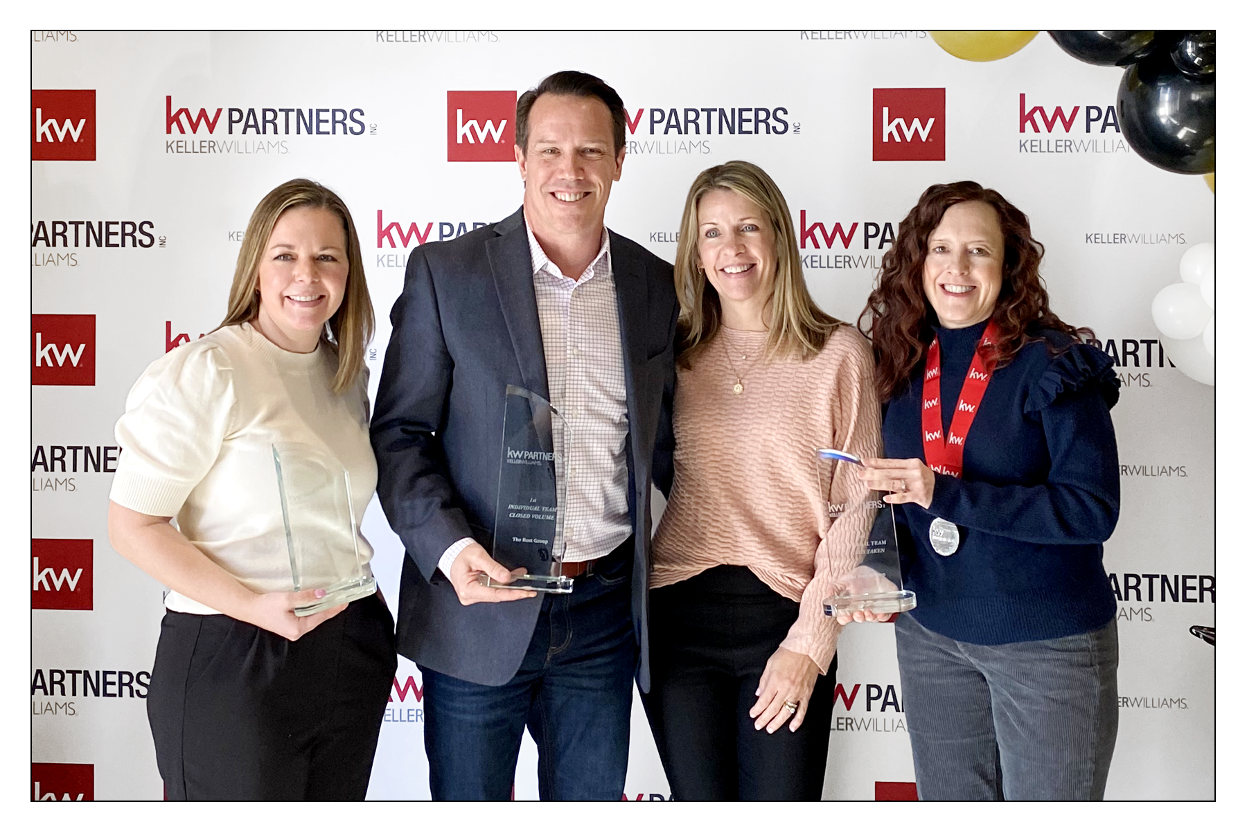 The Rost Group real estate team holding multiple Kansas City Keller Williams awards.