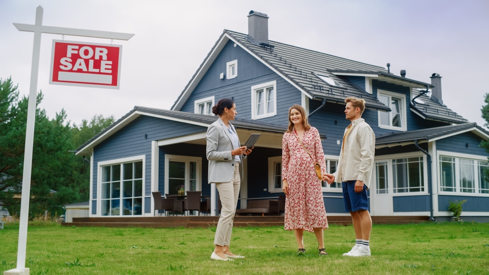 three people talking infront of a house for sale