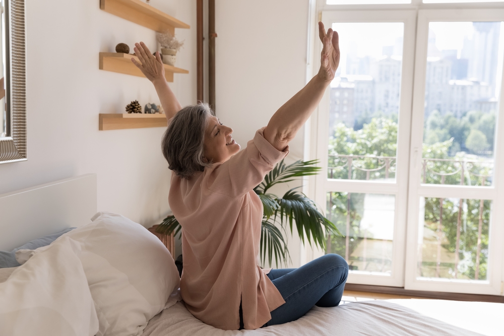 happy senior woman sitting on her bed