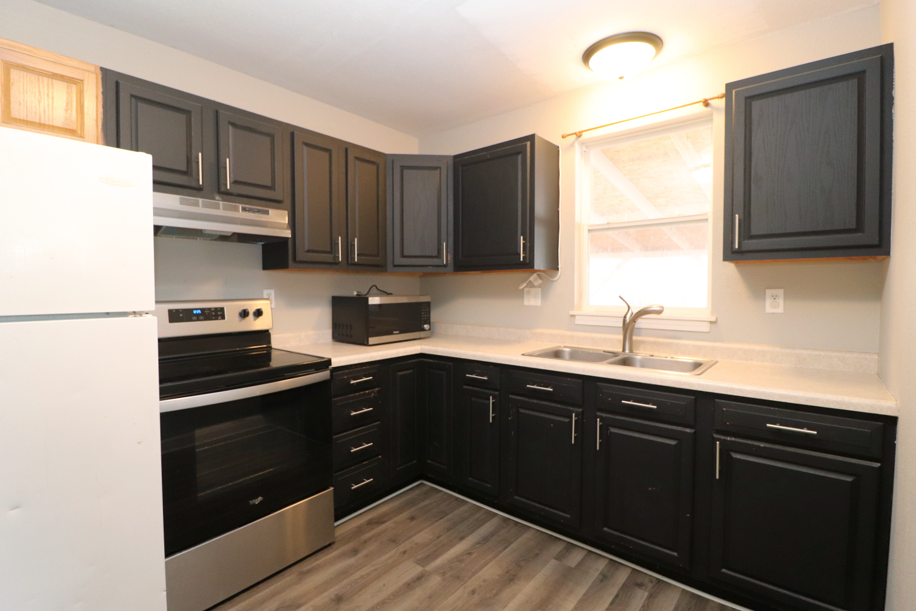 kitchen with black cabinets, updated laminate flooring