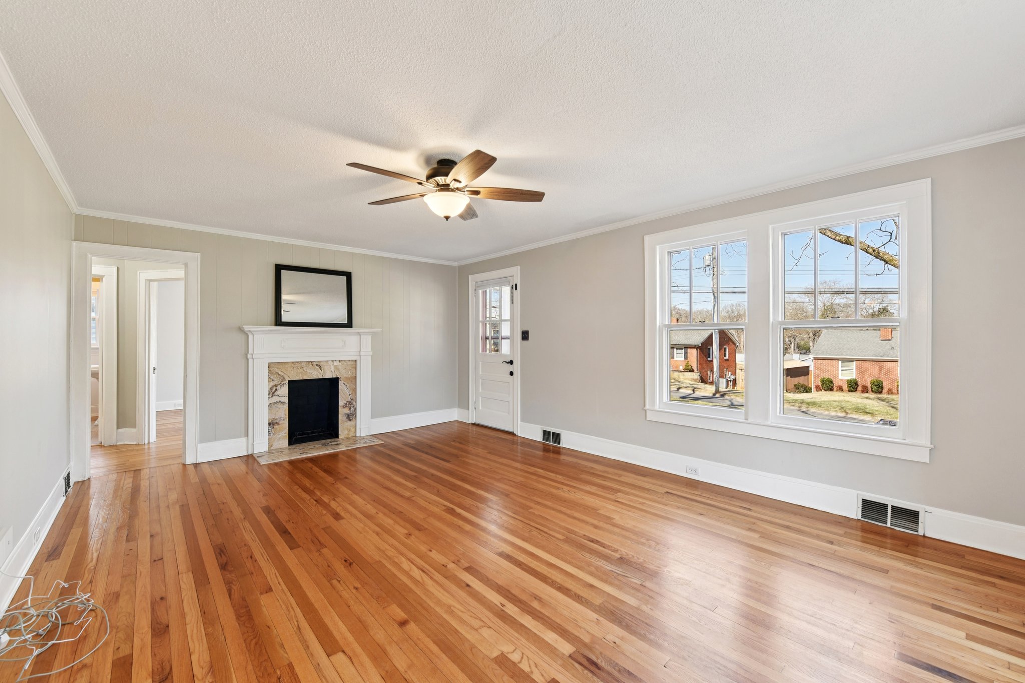 79-fryling-ave-concord-living-room-refinished-oak-floors.jpg Light-filled living room with refinished oak floors and travertine fireplace in renovated Concord North Carolina bungalow.