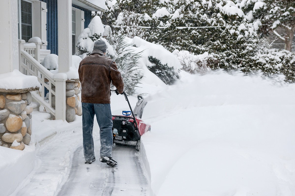 person using snowblower on a house walkway