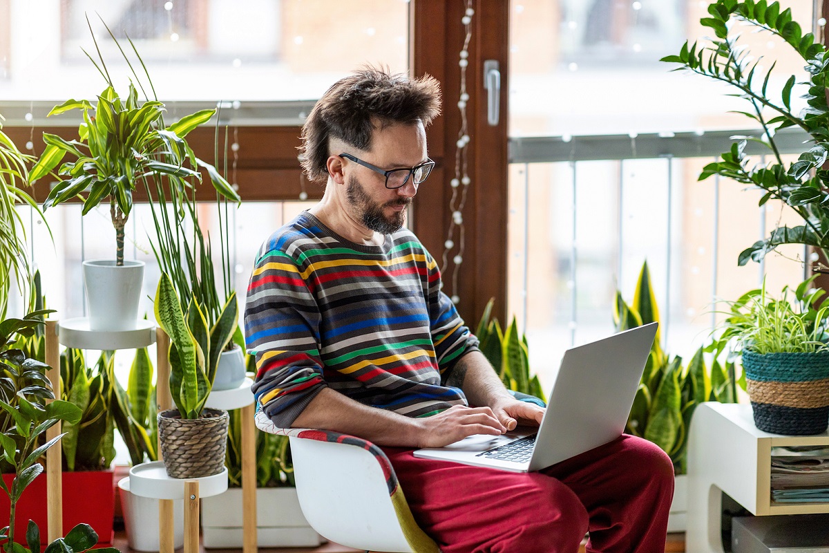 Man working on laptop surrounded by plants