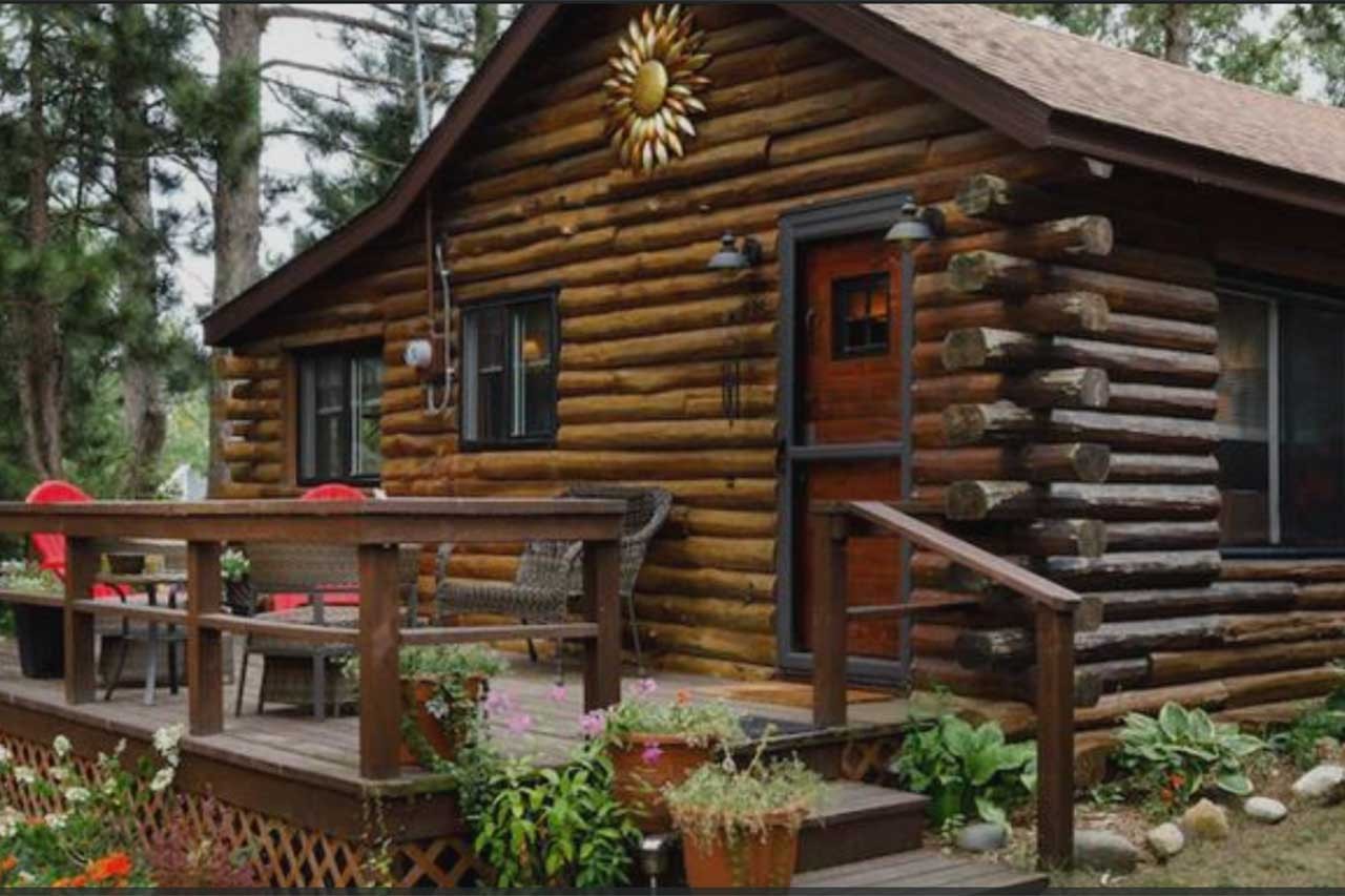 Rustic log cabin with deck and potted flowers, Port Sanilac, MI Real Estate