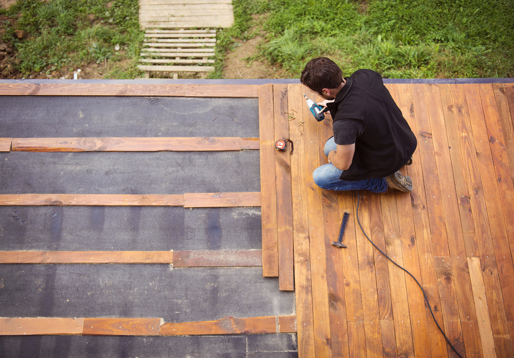 man fixing wooden floor patio