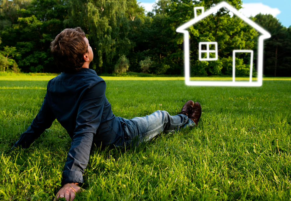 man sitting on the grass thinking about a house