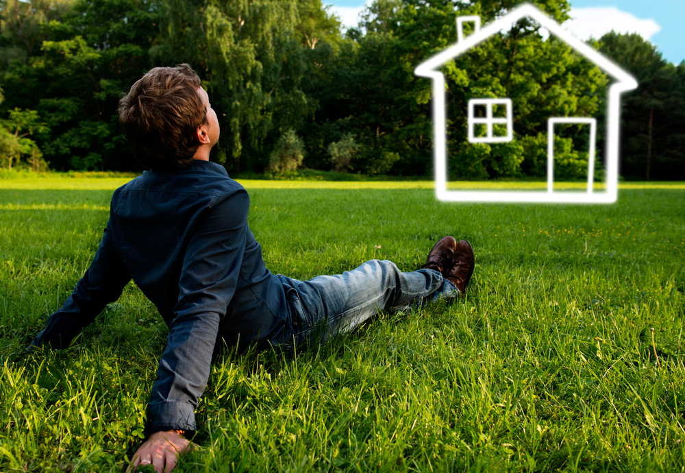 a man sitting on the grass field thinking of his dream home