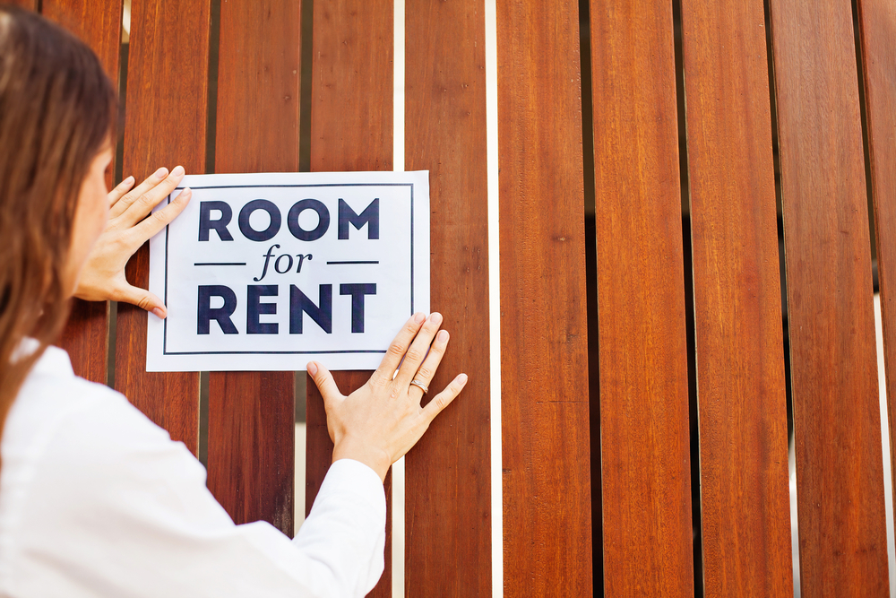 woman posting room for rent sign