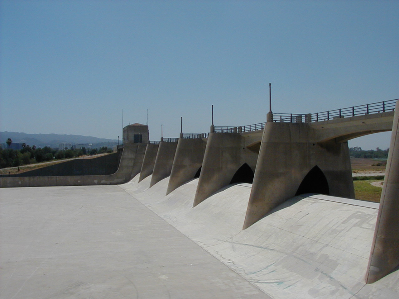 Concrete spillway and flood control structure at Sepulveda Dam in the San Fernando Valley under a clear blue sky.