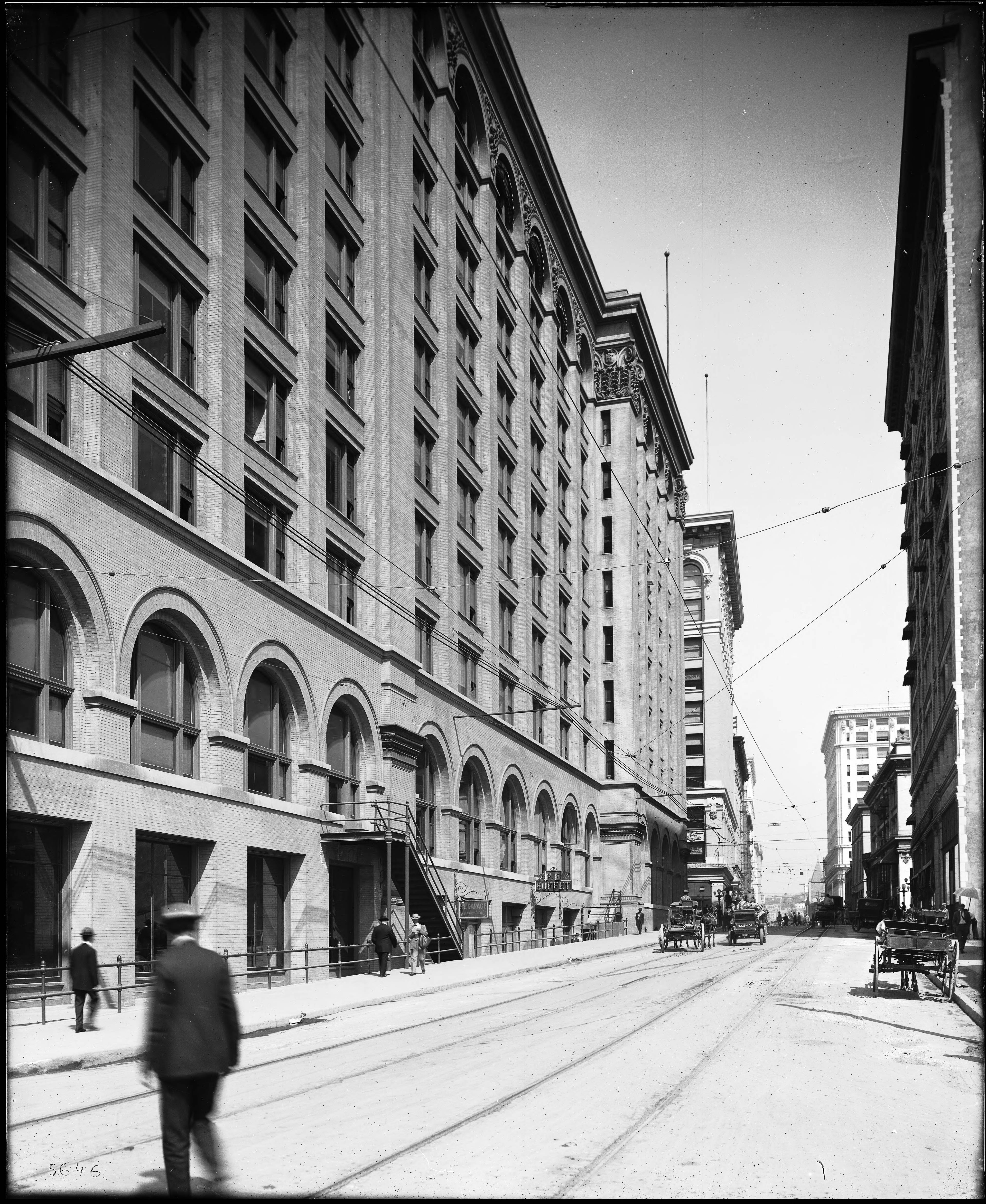 Historic Downtown Los Angeles streetscape, showing the kind of older commercial buildings that later made adaptive reuse so important. Black-and-white historic photograph of Sixth Street in Downtown Los Angeles with tall commercial buildings, streetcar wires, horse-drawn vehicles, pedestrians, and early automobiles.