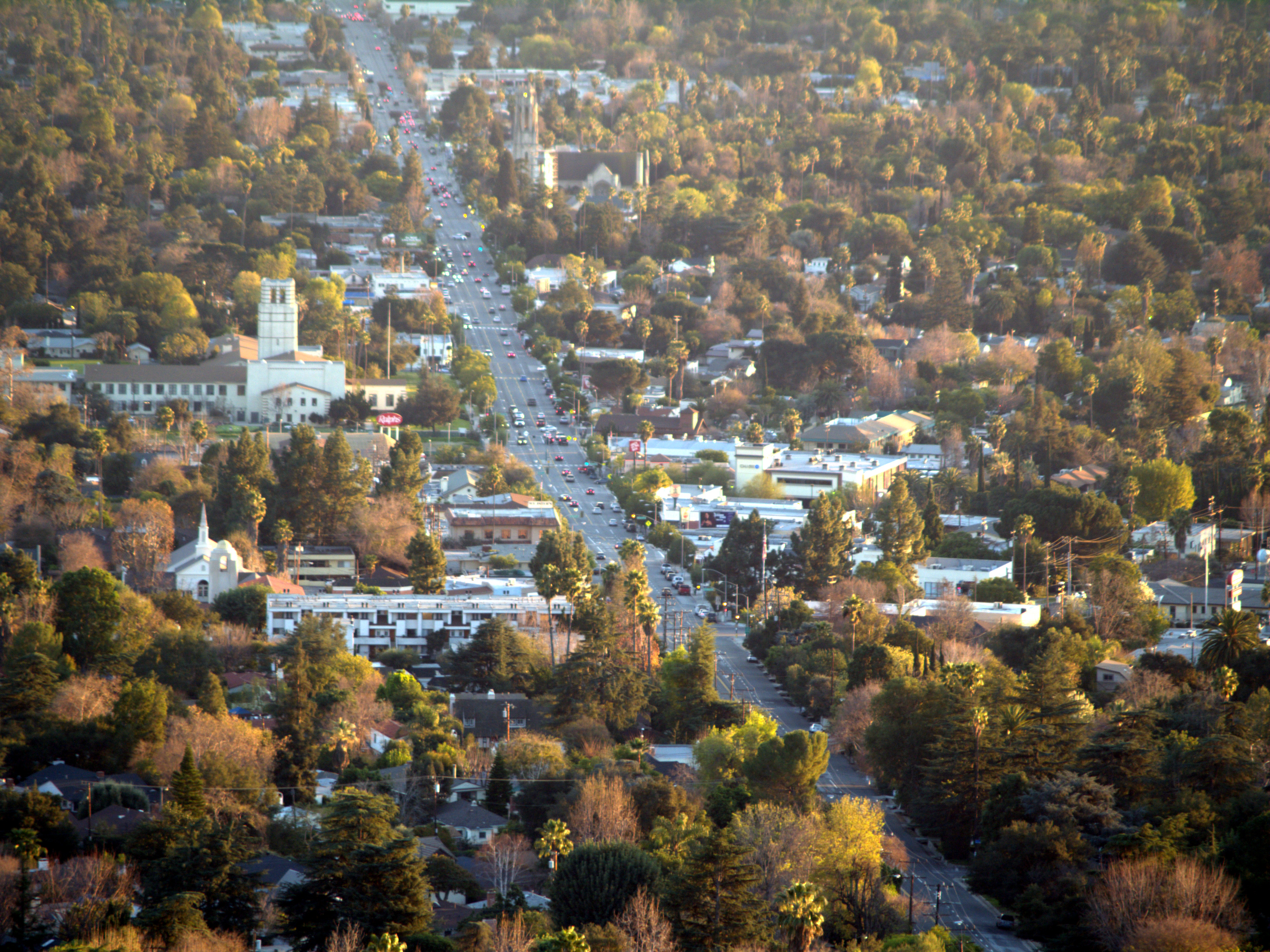 Elevated view looking down Lake Avenue in Altadena with homes, trees, traffic and mountains nearby.