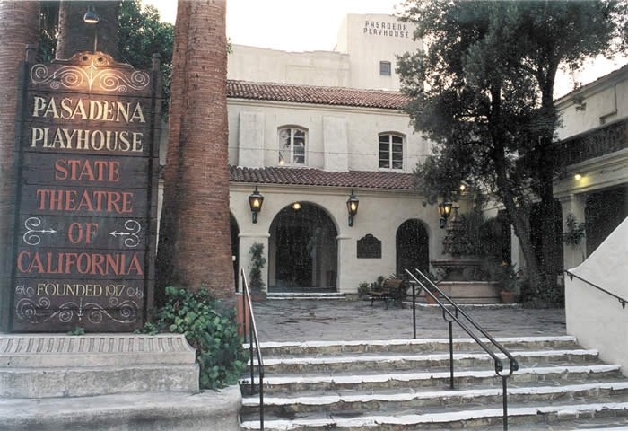 Modern photograph of the Pasadena Playhouse entrance with steps, arched doorways, palm trees and a sign reading State Theatre of California.