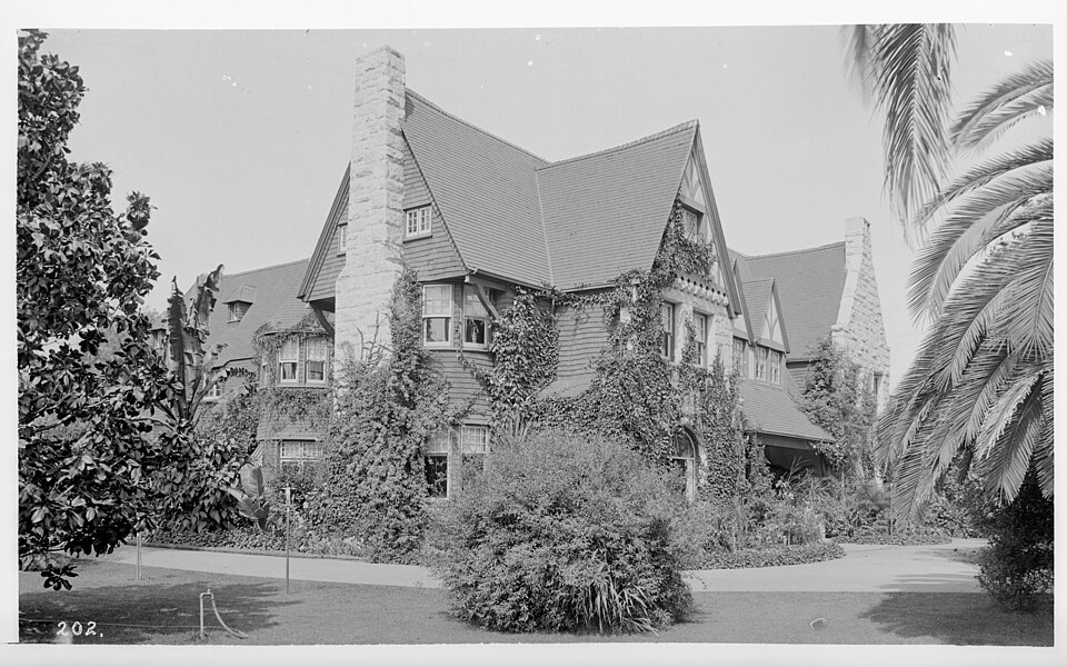 Black-and-white historic photo of the Homer Laughlin home on West Adams Boulevard in Los Angeles, showing a large ivy-covered residence surrounded by gardens and palm trees.