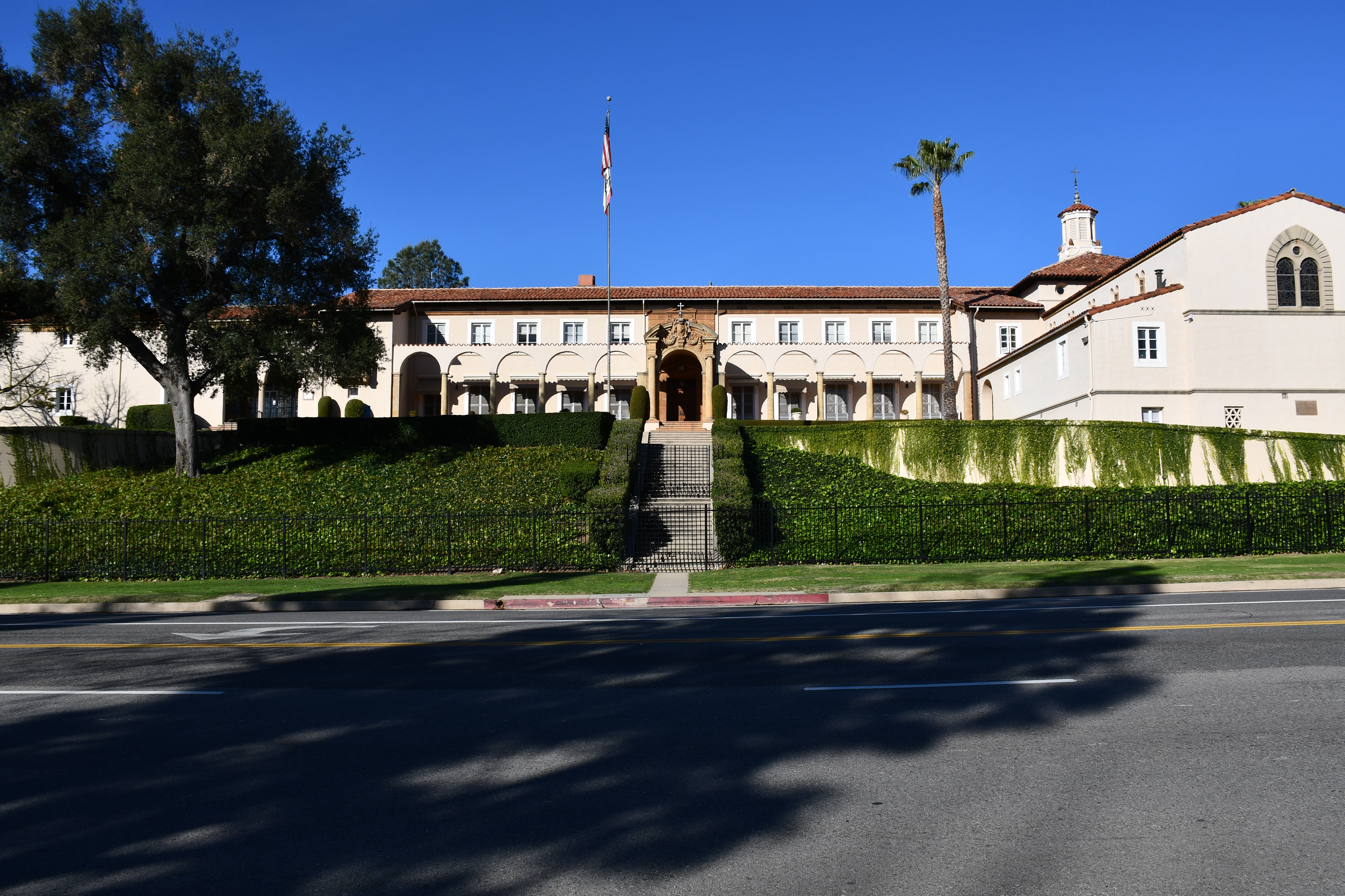 Marymount High School in Bel Air with a long Spanish-style building, red tile roof, arched entry, hedges and blue sky.