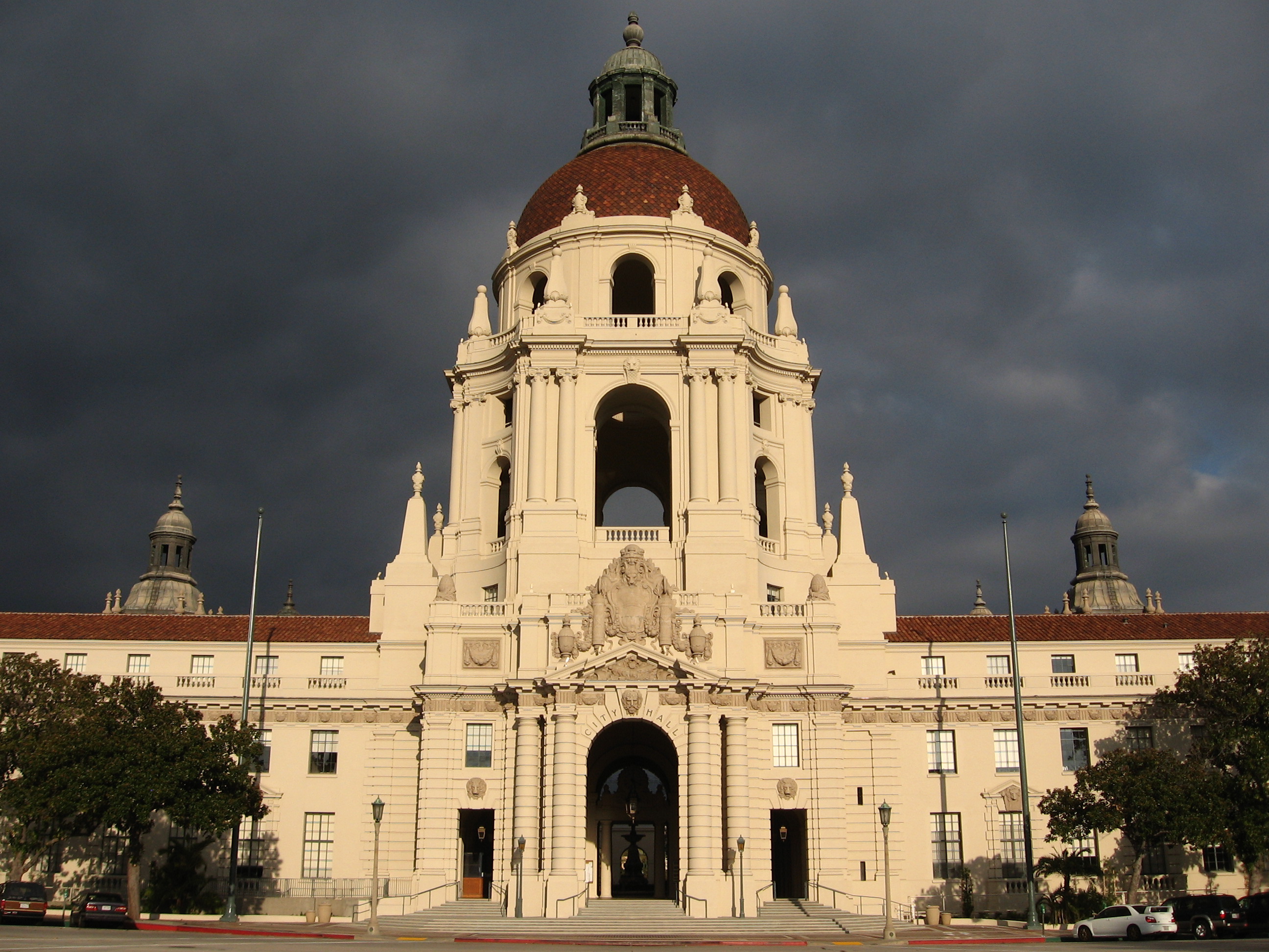Pasadena City Hall with its grand dome, red tile roof, cream-colored façade and dramatic cloudy sky.