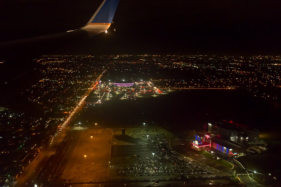 The Forum in Inglewood, the arena that helped define the city’s “City of Champions” identity. Nighttime photograph of the Forum in Inglewood, with the circular arena brightly lit against the dark sky.