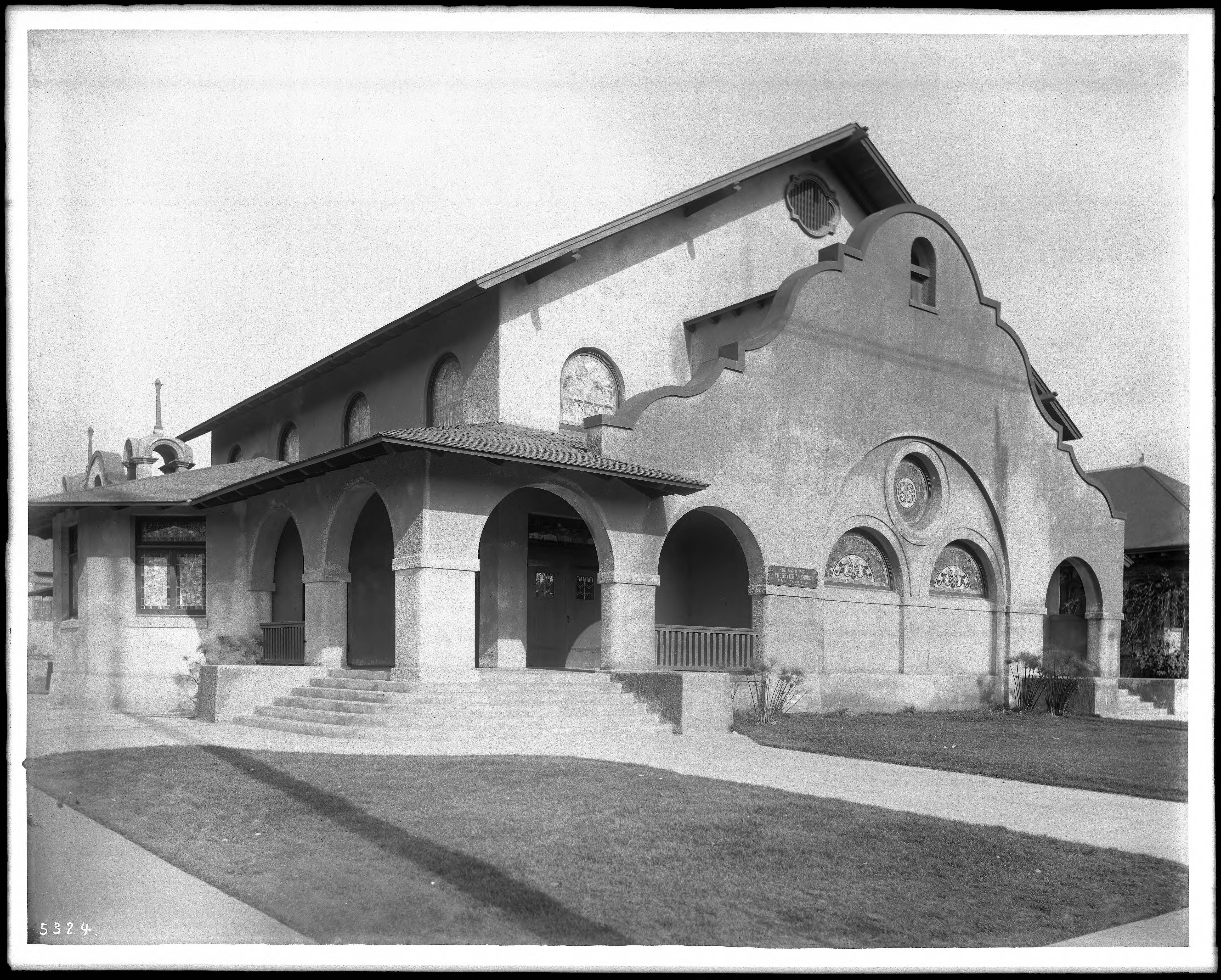 Black-and-white historic photograph of Highland Park Presbyterian Church around 1905, with arched porches, a Mission-style façade, stained glass windows and a lawn.