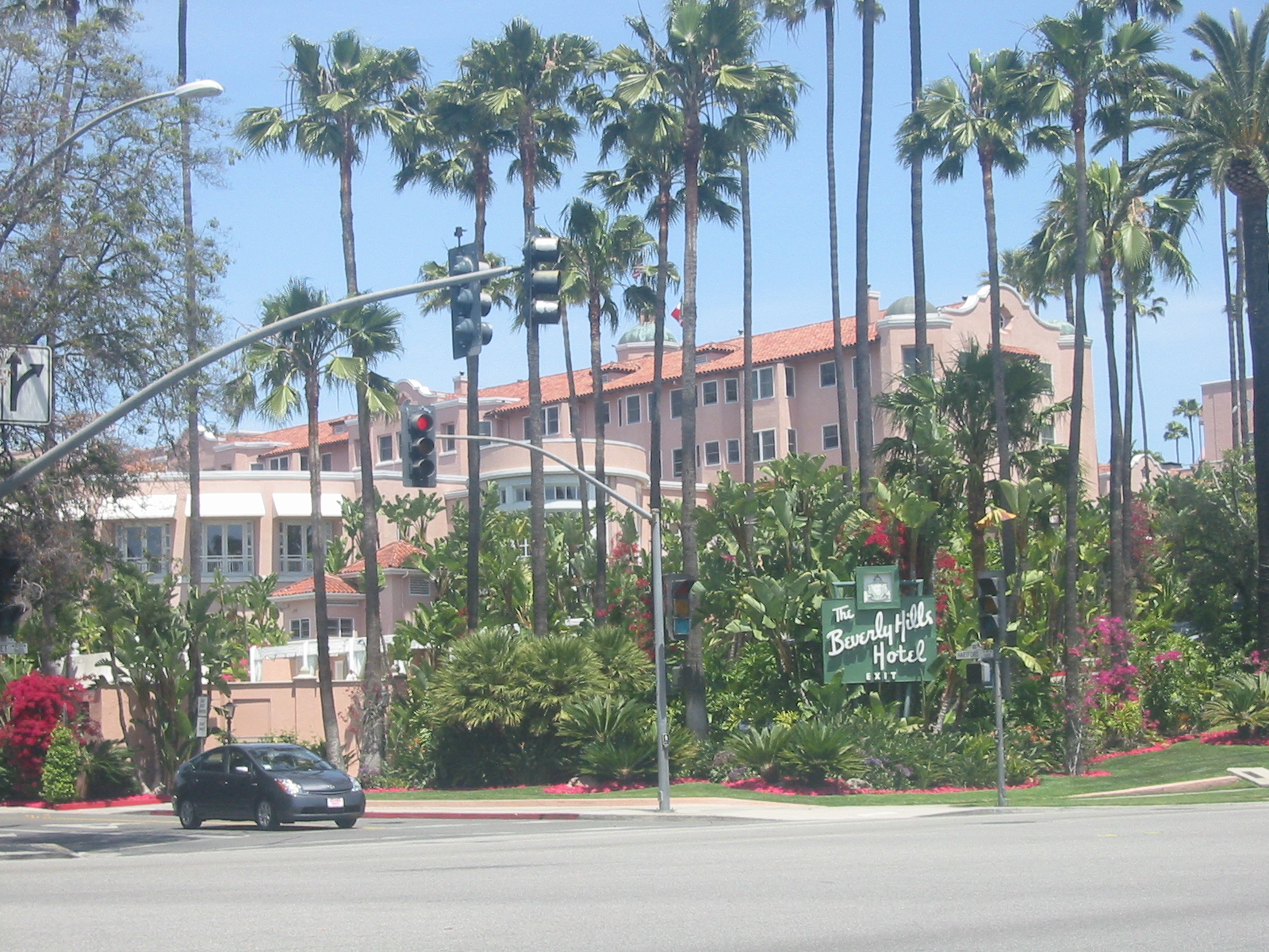 Exterior view of the Beverly Hills Hotel on Sunset Boulevard with palm trees, landscaping and the hotel sign visible.