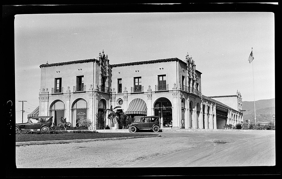 A Pacific Palisades business block in 1925, showing the early village character of the community. Black-and-white photograph of a Spanish-style business block in Pacific Palisades in 1925, with early automobiles parked along the street.