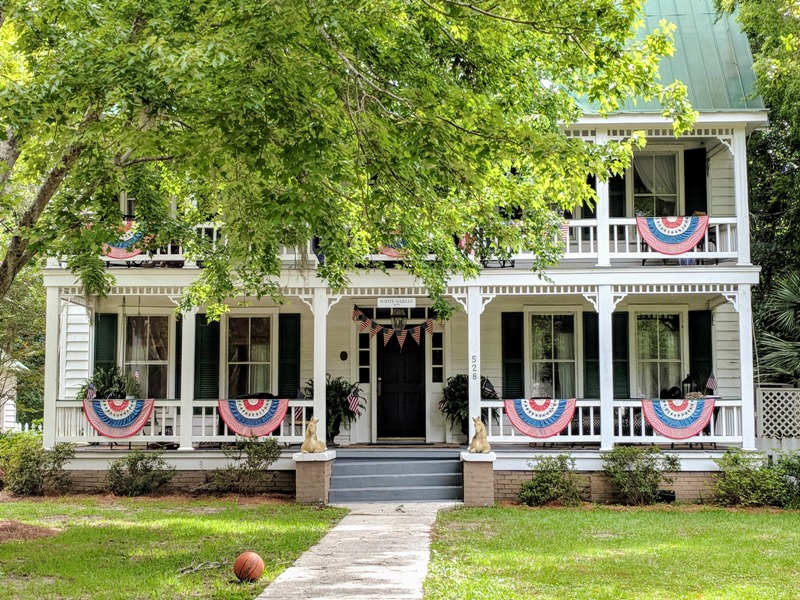 Historic-style coastal home exterior with porch and landscaping