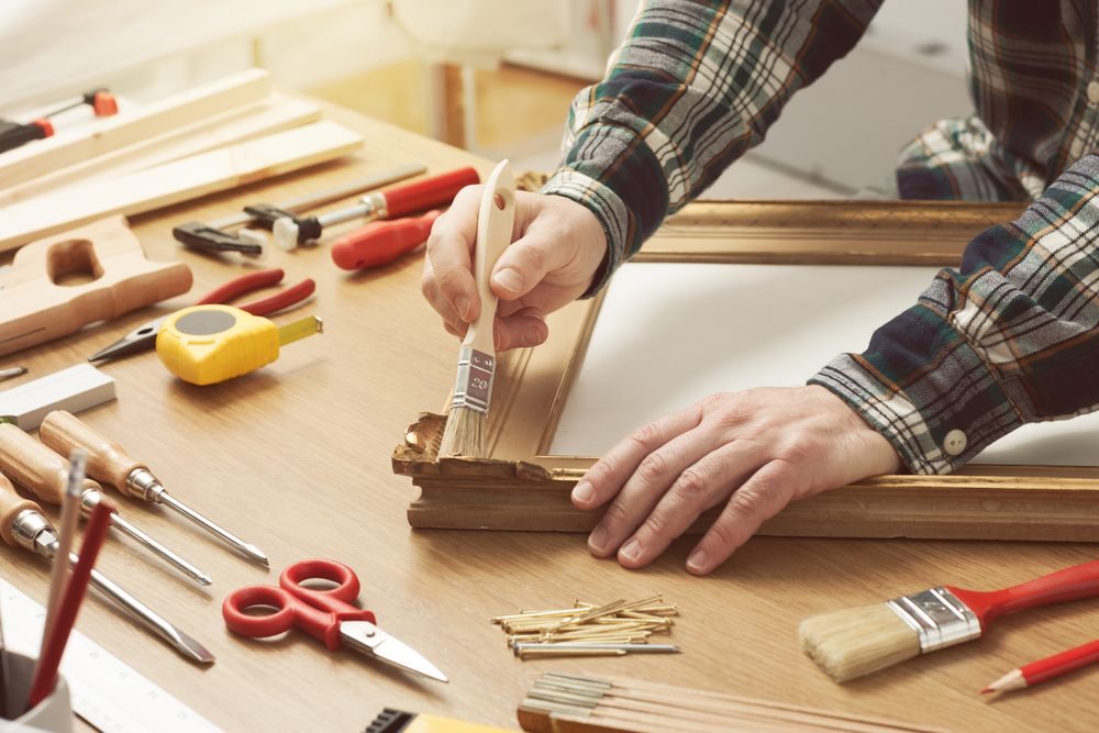 a person using brush in painting the wood frame