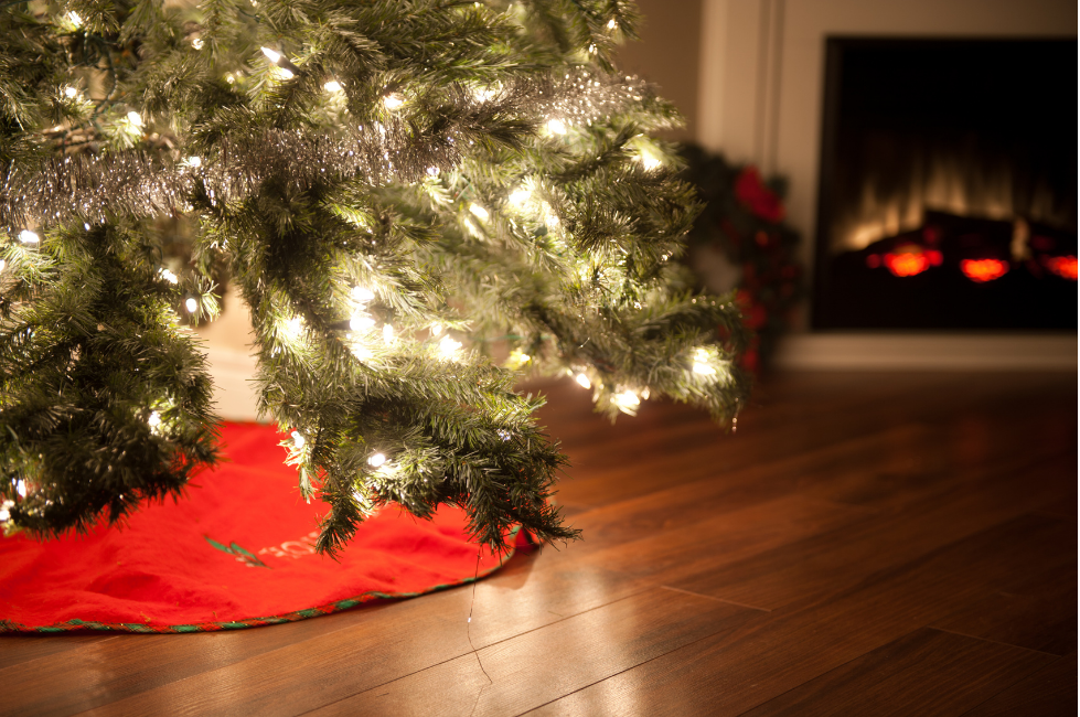 lit christmas tree with fireplace in the background, home safety tips during the holidays
